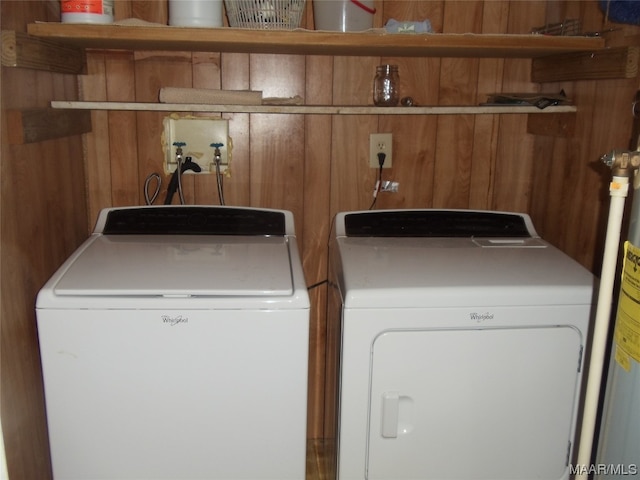 clothes washing area featuring wooden walls, washer and clothes dryer, and washer hookup