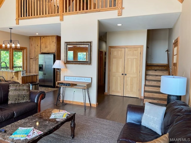 living area with recessed lighting, baseboards, dark wood-style floors, and a towering ceiling