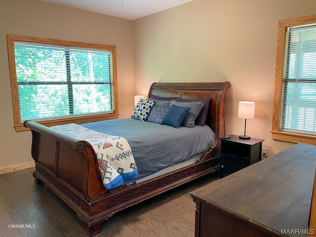 bedroom with multiple windows and dark hardwood / wood-style floors