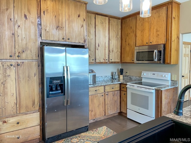 kitchen featuring stone counters, decorative light fixtures, appliances with stainless steel finishes, and dark hardwood / wood-style flooring