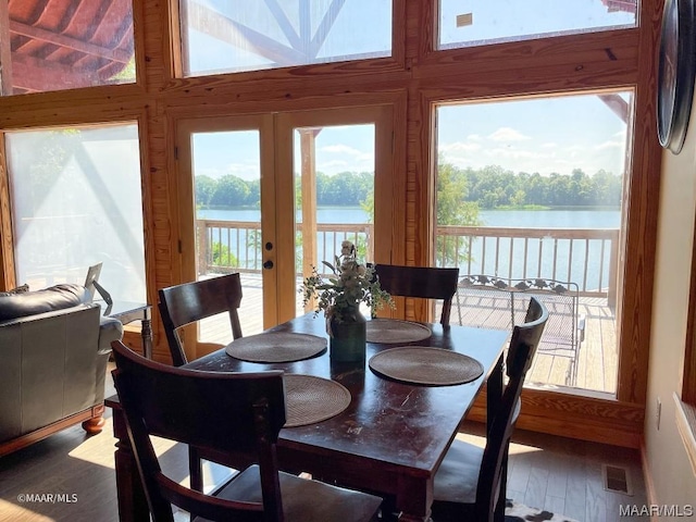 dining space featuring a water view, visible vents, and wood finished floors