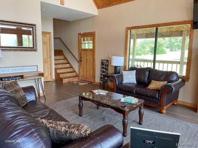 living area with baseboards, plenty of natural light, wood finished floors, and stairway