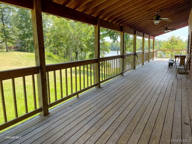 wooden terrace with a lawn, a water view, and a ceiling fan