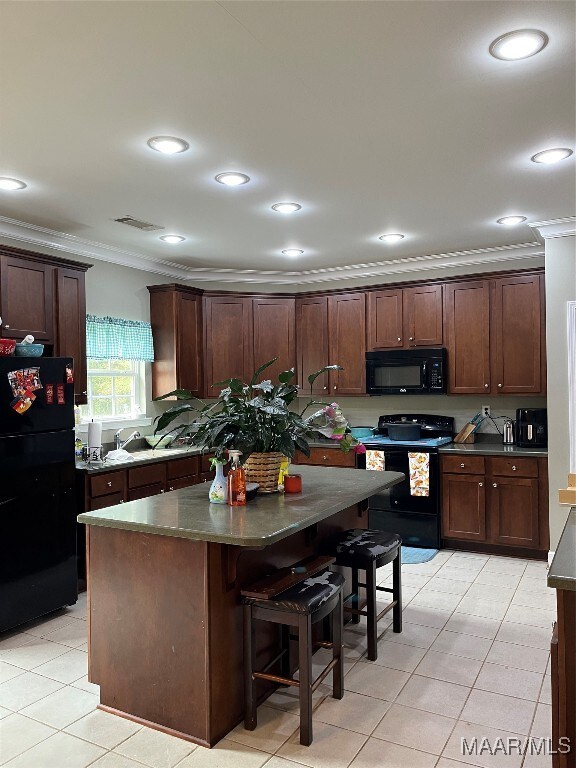 kitchen with dark brown cabinets, a kitchen island, ornamental molding, and black appliances