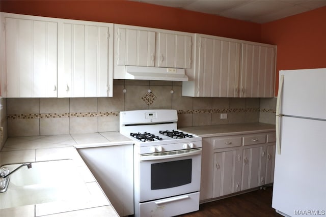 kitchen with white cabinetry, white appliances, sink, tasteful backsplash, and dark hardwood / wood-style flooring