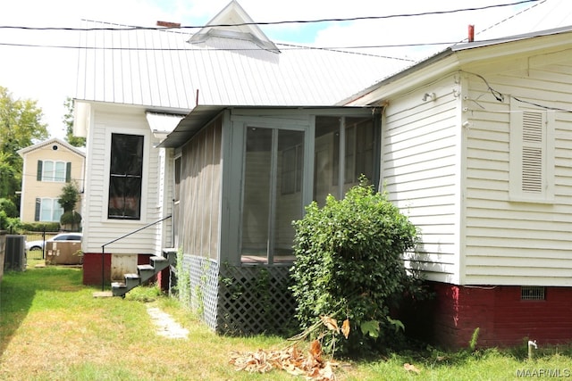 view of side of home with a lawn and a sunroom