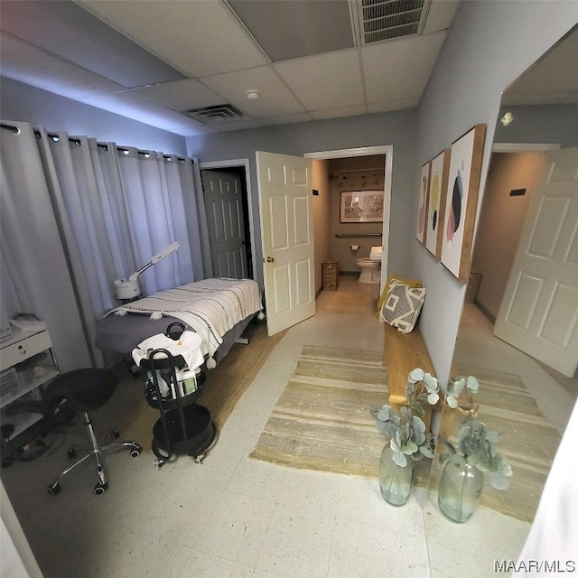 bedroom featuring a paneled ceiling, ensuite bathroom, and light tile floors