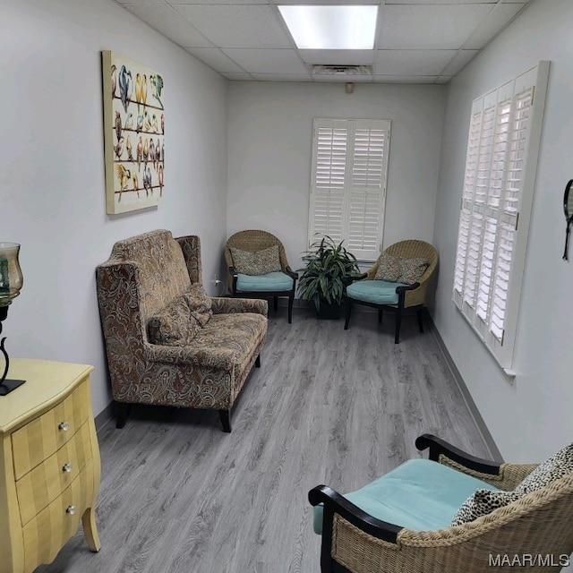 sitting room featuring light hardwood / wood-style flooring and a drop ceiling