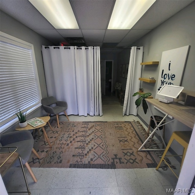 sitting room with light tile flooring and a drop ceiling