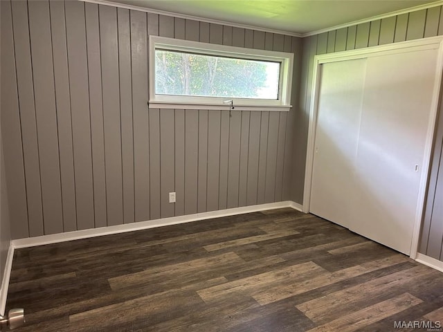 unfurnished bedroom featuring a closet, dark wood-type flooring, and ornamental molding