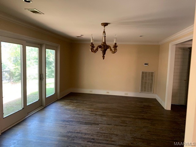 unfurnished room featuring dark hardwood / wood-style flooring, a notable chandelier, ornamental molding, and a wealth of natural light