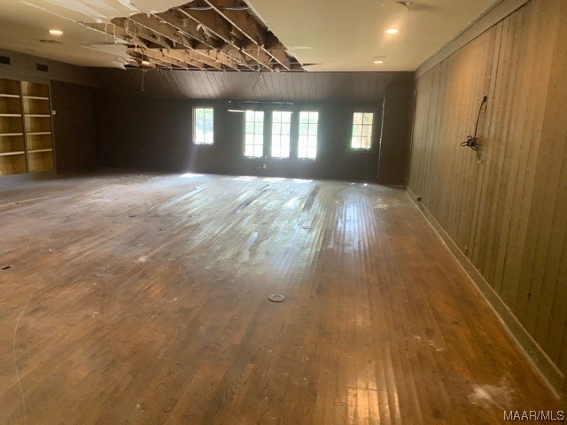 interior space featuring built in features, wood-type flooring, and wood walls