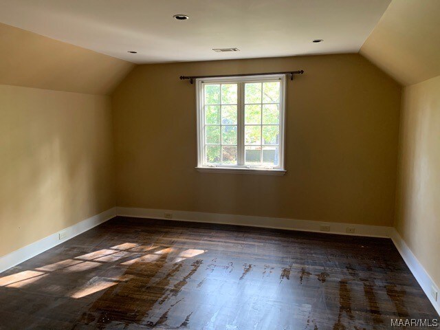 additional living space featuring lofted ceiling and dark hardwood / wood-style flooring