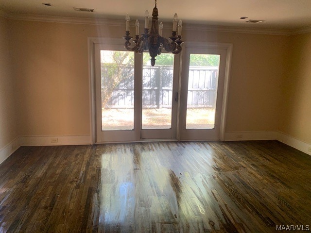 spare room featuring a chandelier, a wealth of natural light, and dark hardwood / wood-style flooring