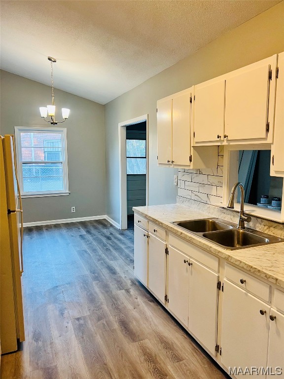 kitchen with decorative light fixtures, white fridge, light hardwood / wood-style flooring, white cabinets, and a chandelier