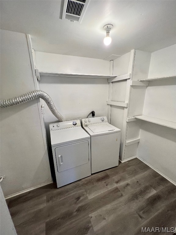 laundry room with washing machine and clothes dryer and dark hardwood / wood-style flooring