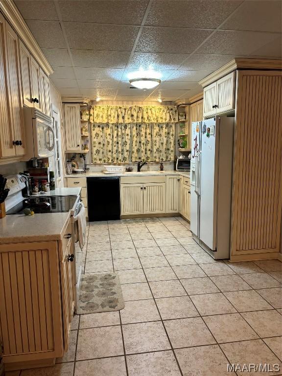 kitchen featuring sink, light tile patterned flooring, a drop ceiling, and white appliances