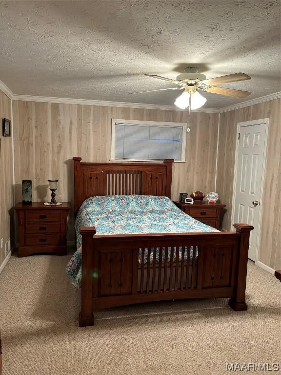 bedroom featuring crown molding, wooden walls, ceiling fan, a textured ceiling, and carpet floors