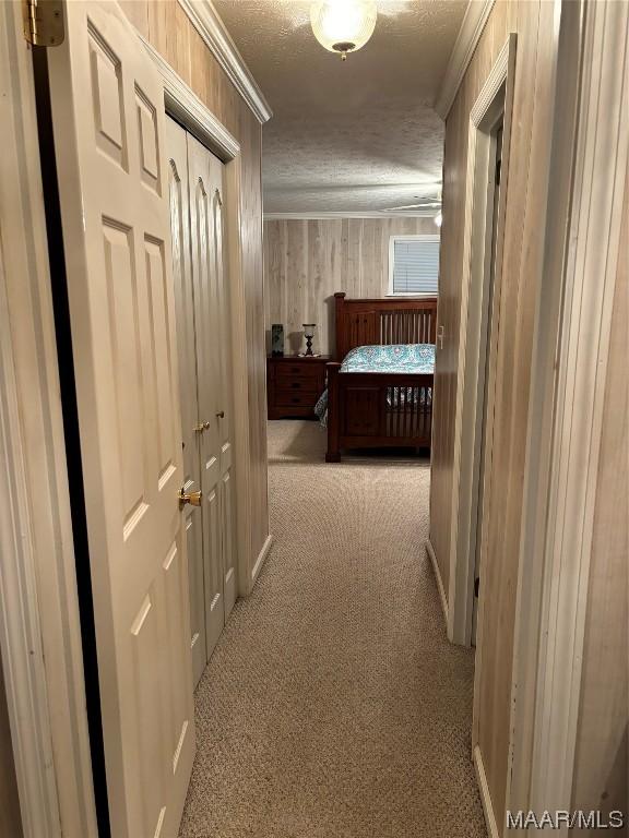 hallway featuring light colored carpet and a textured ceiling