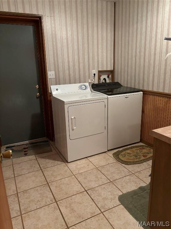 clothes washing area featuring washer and dryer, wooden walls, and light tile patterned flooring