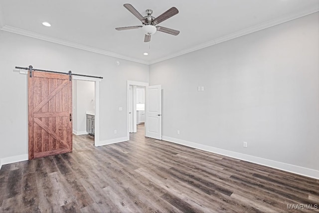 unfurnished bedroom featuring ornamental molding, a barn door, ceiling fan, and ensuite bathroom