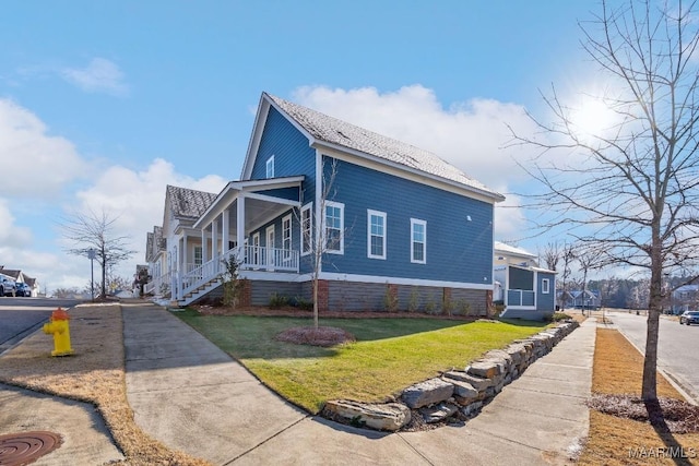 view of side of home with a porch and a lawn