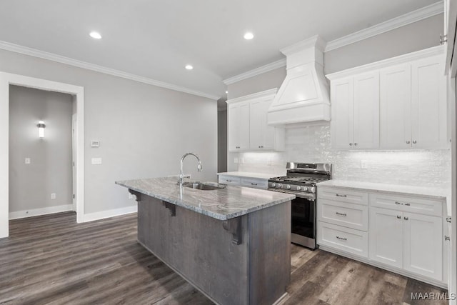 kitchen with an island with sink, white cabinetry, sink, custom exhaust hood, and stainless steel gas range oven