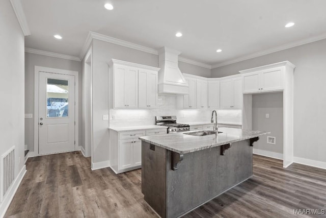 kitchen featuring stainless steel range oven, sink, custom exhaust hood, and white cabinets