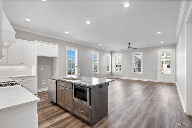 kitchen with light stone counters, dishwasher, sink, and white cabinets