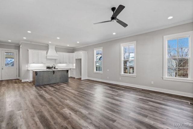 unfurnished living room with sink, ornamental molding, dark hardwood / wood-style floors, and ceiling fan