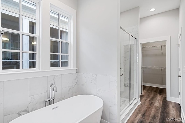 bathroom featuring tile walls, wood-type flooring, and separate shower and tub