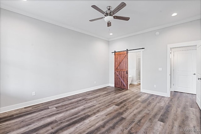 unfurnished bedroom featuring ornamental molding, a barn door, dark wood-type flooring, and ceiling fan