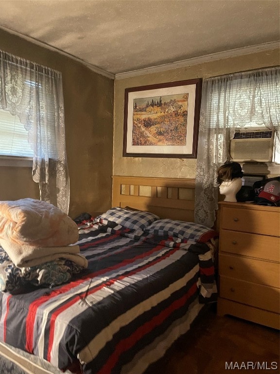 bedroom with ornamental molding, dark wood-type flooring, and a textured ceiling