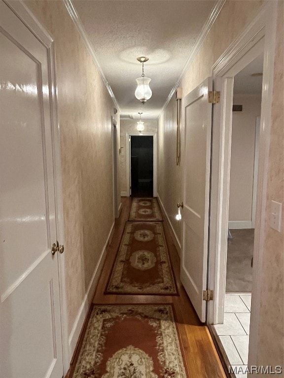 hall with a textured ceiling, dark wood-type flooring, and ornamental molding