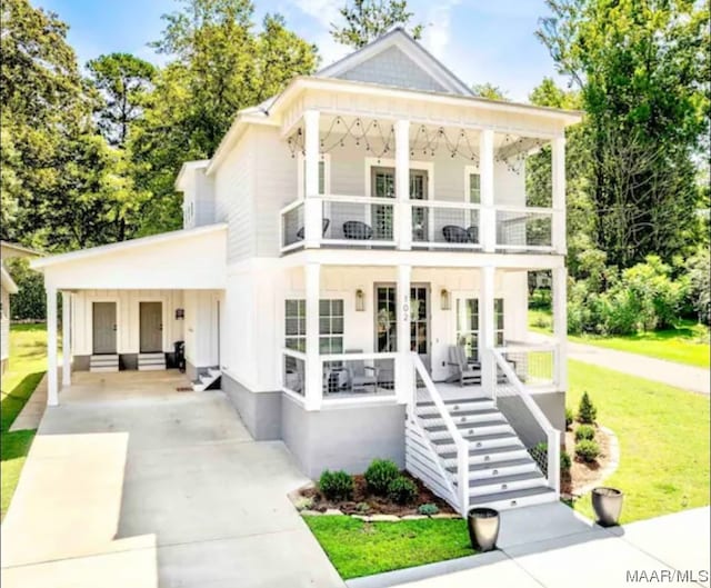 neoclassical home featuring a balcony and a front yard