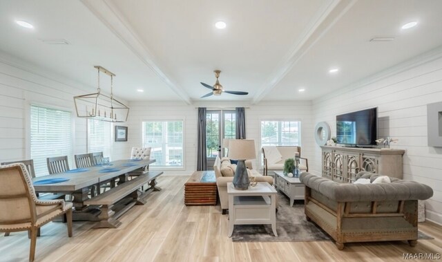 living room with beam ceiling, light hardwood / wood-style floors, and ceiling fan with notable chandelier