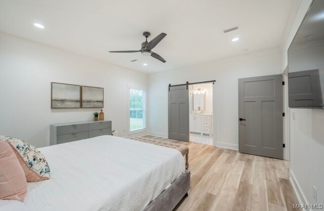 bedroom featuring connected bathroom, ceiling fan, ornamental molding, a barn door, and light wood-type flooring