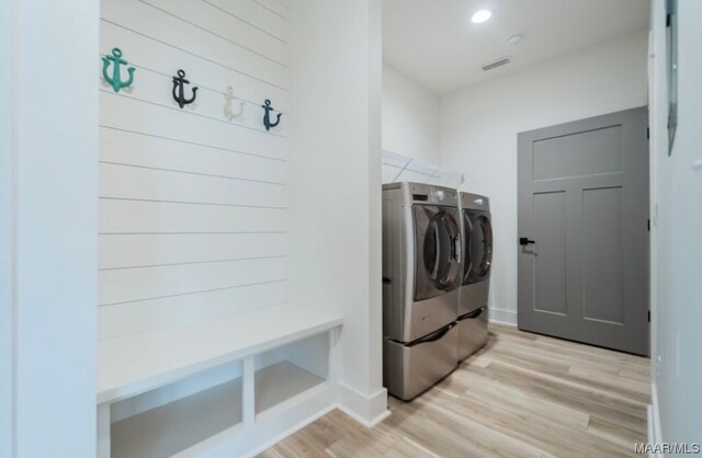 washroom with light hardwood / wood-style floors and washing machine and dryer