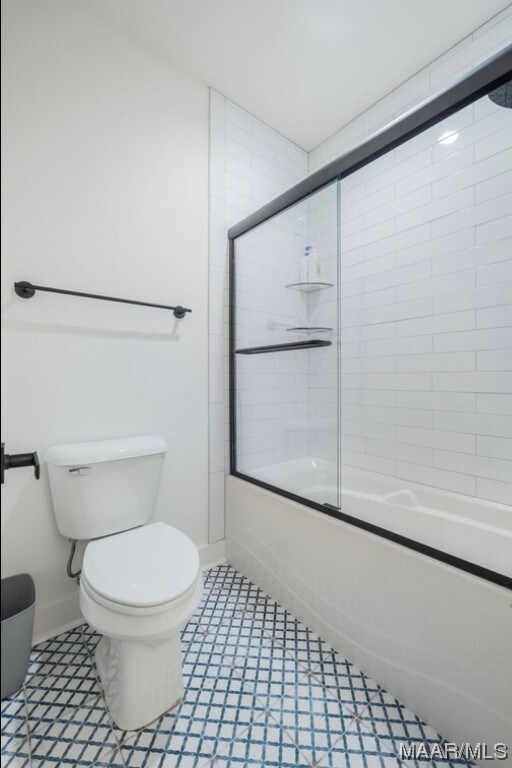 bathroom with shower / bath combination with glass door, tile floors, and toilet