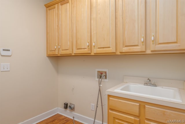 laundry room featuring hookup for a washing machine, wood-type flooring, electric dryer hookup, sink, and cabinets