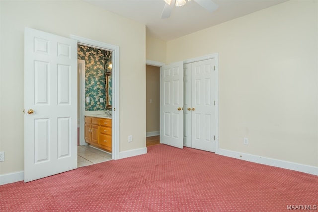 unfurnished bedroom featuring light carpet, a closet, ceiling fan, and ensuite bath