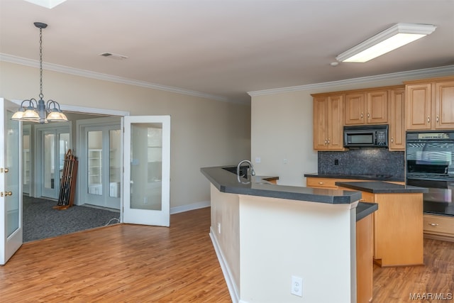 kitchen featuring backsplash, black appliances, a center island, light wood-type flooring, and pendant lighting