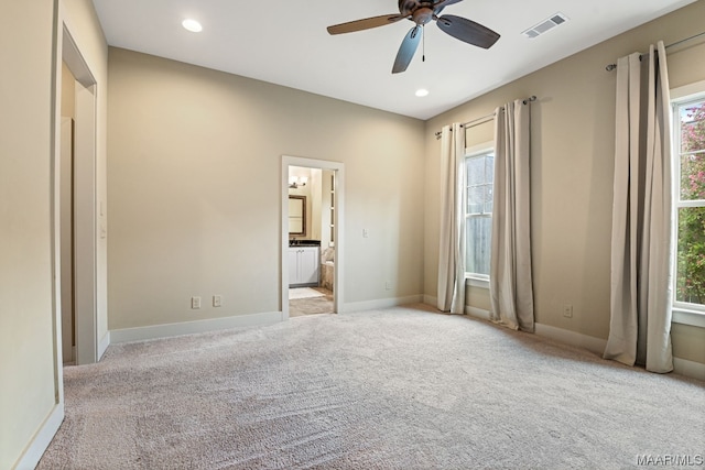 unfurnished bedroom featuring light carpet, ensuite bathroom, and ceiling fan