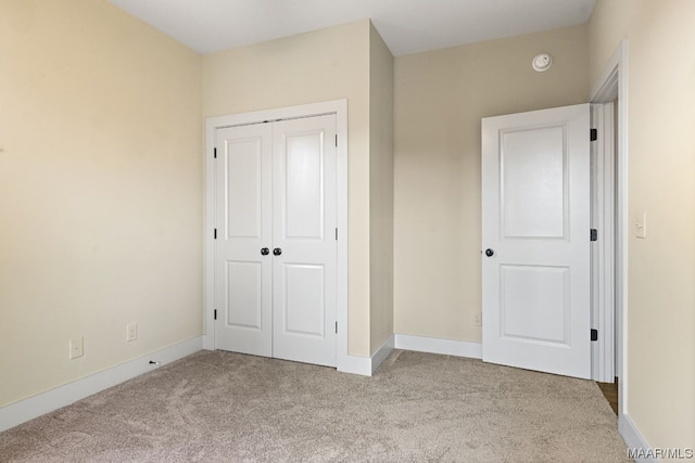 unfurnished bedroom featuring light carpet and a closet