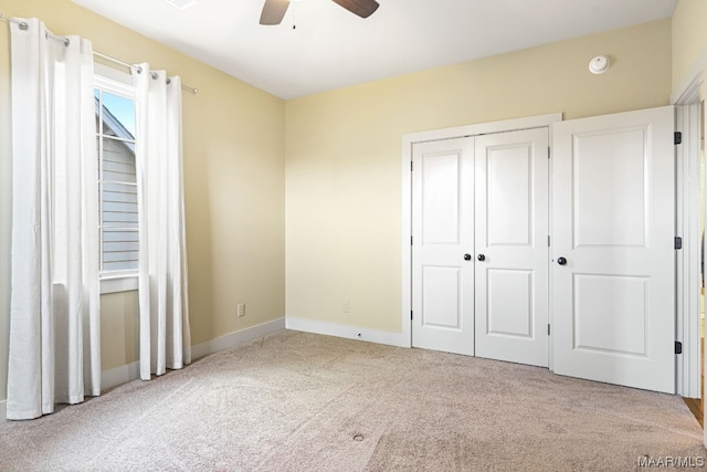 unfurnished bedroom featuring light carpet, a closet, and ceiling fan