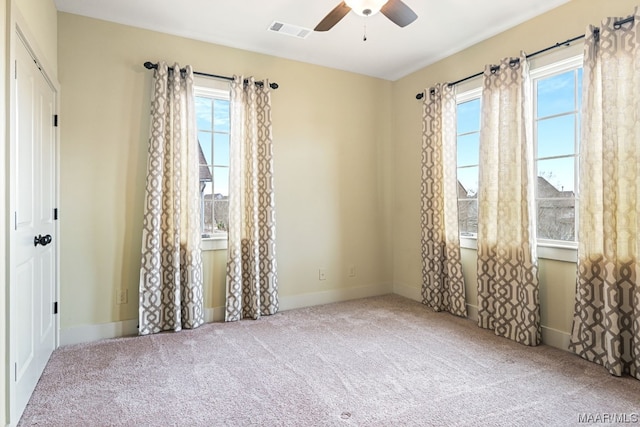 carpeted spare room featuring ceiling fan and a healthy amount of sunlight