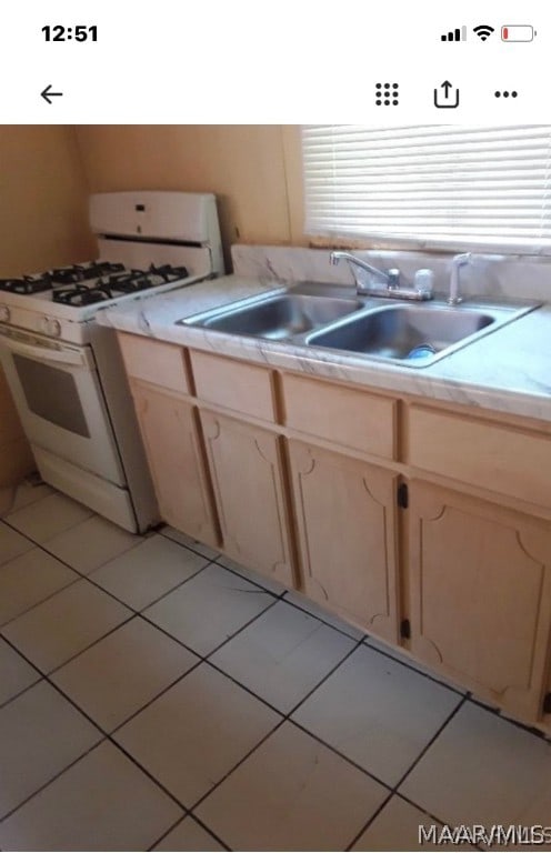 kitchen featuring light brown cabinetry, white range with gas stovetop, sink, and light tile flooring