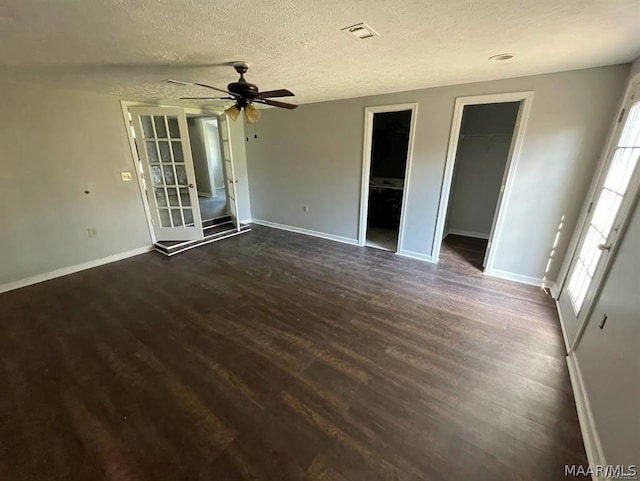 unfurnished bedroom with a walk in closet, a textured ceiling, dark hardwood / wood-style floors, and ceiling fan