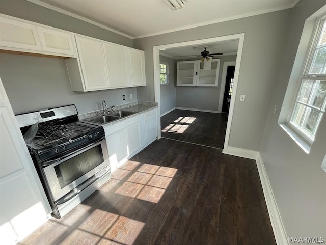 kitchen with stainless steel gas stove, dark wood-type flooring, ceiling fan, sink, and white cabinetry