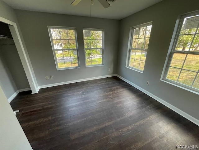 empty room featuring dark hardwood / wood-style floors, ceiling fan, and a healthy amount of sunlight